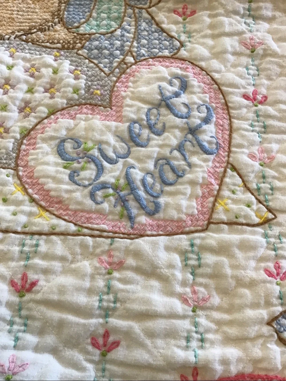 Vintage handmade baby quilt featuring embroidered teddy bears